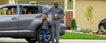 a child wearing a backpack being dropped off by adults